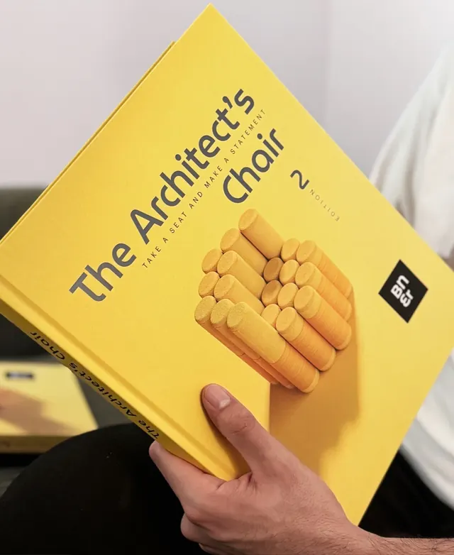 The yellow Architect’s Chair 02 book held in a reader’s hands
