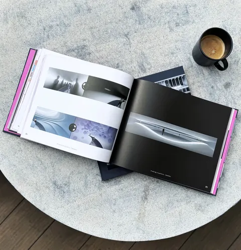 The book open on a round stone table at a black page with a long white hall