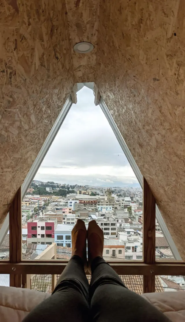 Lying in bed under the triangular window, feet up, the rooftops of Quito outside