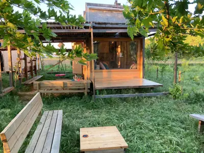 The cabin five years on, with a new porch, a canopy and benches under the trees