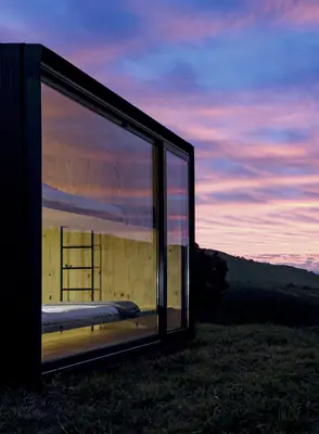The dark frame and glass wall of a MINIMOD unit against a pink and purple evening sky