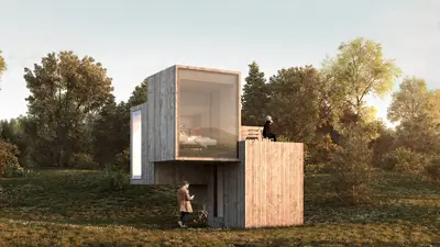 Two stacked timber boxes, the upper one with a big window, in a meadow at sunset