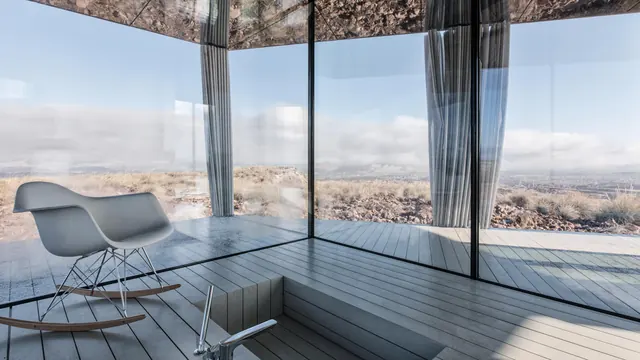 Inside: a rocking chair behind floor-to-ceiling glass, the desert beyond