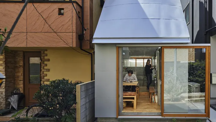 Love2 House from the lane: a narrow white house with a glass front, open to the street, between its neighbours