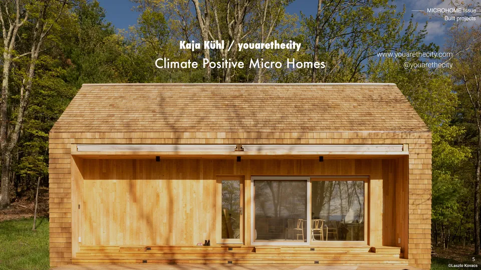 Climate Positive Micro Homes: a timber cabin with a wide glass front in a forest, with its title