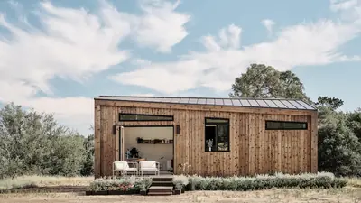 A long timber cabin with a kinked metal roof on a grassy field