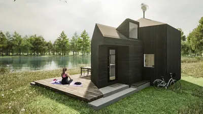 A black cabin of steep gables by a lake, a deck in front and a bicycle beside it