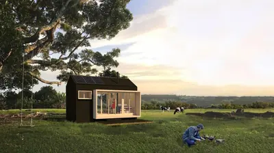 A small black house with a lit glass corner in a green field under a big tree
