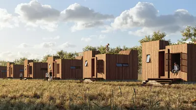 A row of timber blocks with trapezoid roofs on a dry grassy lot