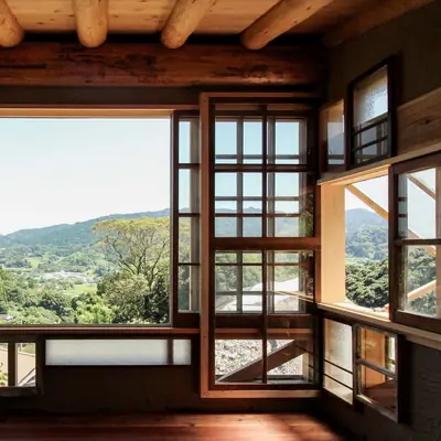 Old wooden windows of many sizes in a timber room, green hills beyond