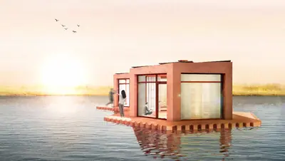 A terracotta-coloured house on a floating platform on a calm lake at sunrise