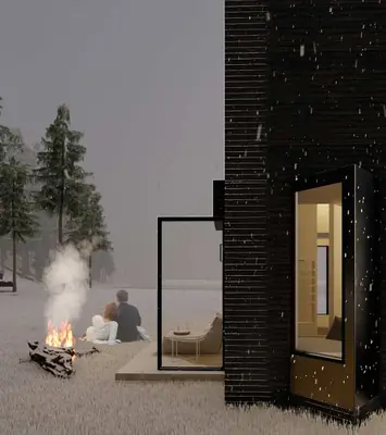 A black cabin lit from inside at dusk, two people by a campfire beside it
