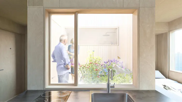 The kitchen: a sink and hob under a big window onto a small courtyard garden, two people standing among the flowers