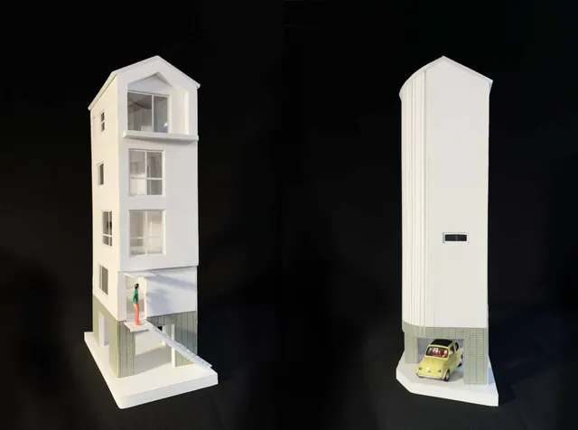 Two white models of the house on black: one open to show its stacked floors and stairs, one closed