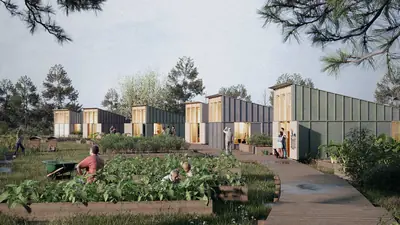Small houses with steep roofs behind shared vegetable beds, people gardening