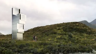A tall white tower of stacked boxes on a green hill, two people walking below