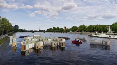 A cluster of small floating homes on a wide river in a city