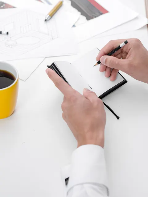 Writing with the pencil on a white page of the notebook