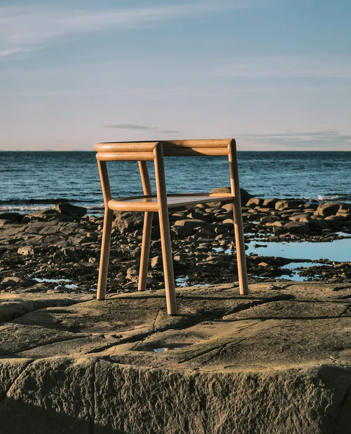 An Elsie chair in pale solid wood on the rocks by the sea