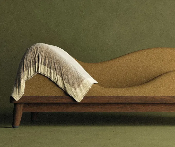 The Mountains Chair, a cork chaise with a draped blanket, on a dark oak base