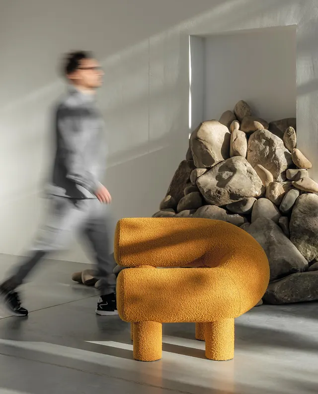 A man walking past an orange Umi Armchair