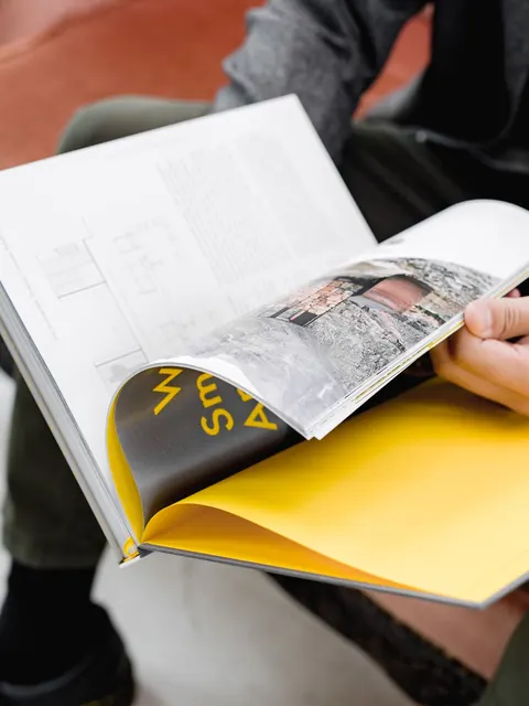 El libro abierto en el regazo por la guarda amarilla, con el título en amarillo sobre azul oscuro