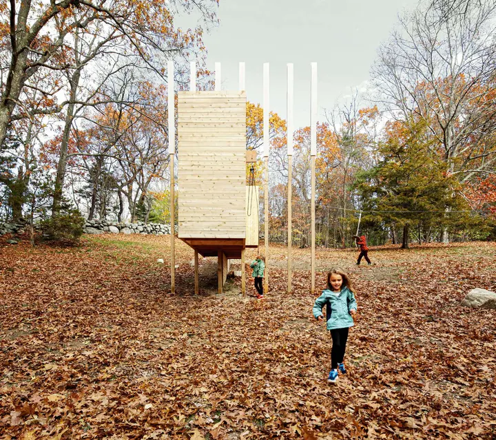 La torre de juegos de madera sobre un campo de hojas otoñales, con niños alrededor