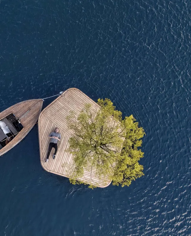 La isla y un bote de remos vistos desde arriba, sobre el agua azul oscuro