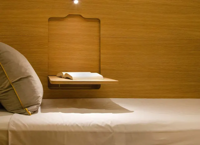 Dentro de un Sleepbox: una cama hecha, un estante y cálidas paredes de madera