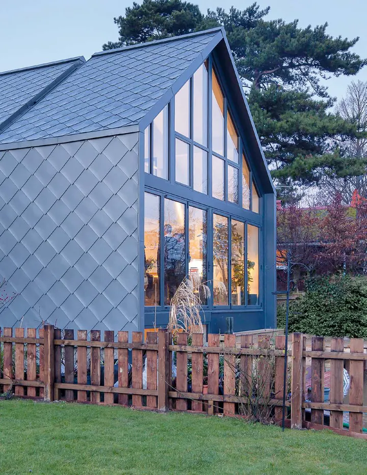The gable end of the house: full-height glass and a skin of diamond-shaped metal shingles