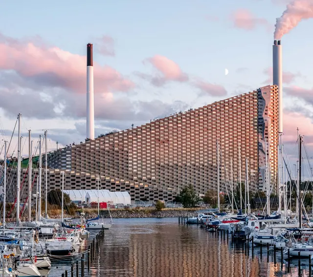 The stepped aluminium façade seen across a marina at dusk